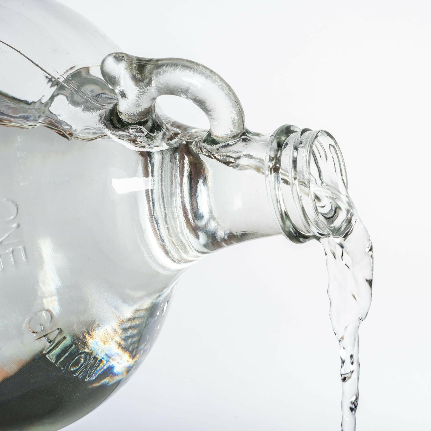One gallon glass bottle of DMSO product being poured out. This photo is used to show consistency of product.