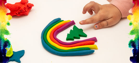 hand arranging a rainbow made from Baking Soda or citric Acid "play dough"