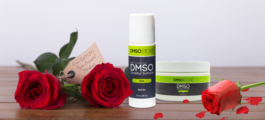 DMSO rose-scented roll-on and gel on wood counter with roses and a tag that says "New DMSO Rose-Scented Products"