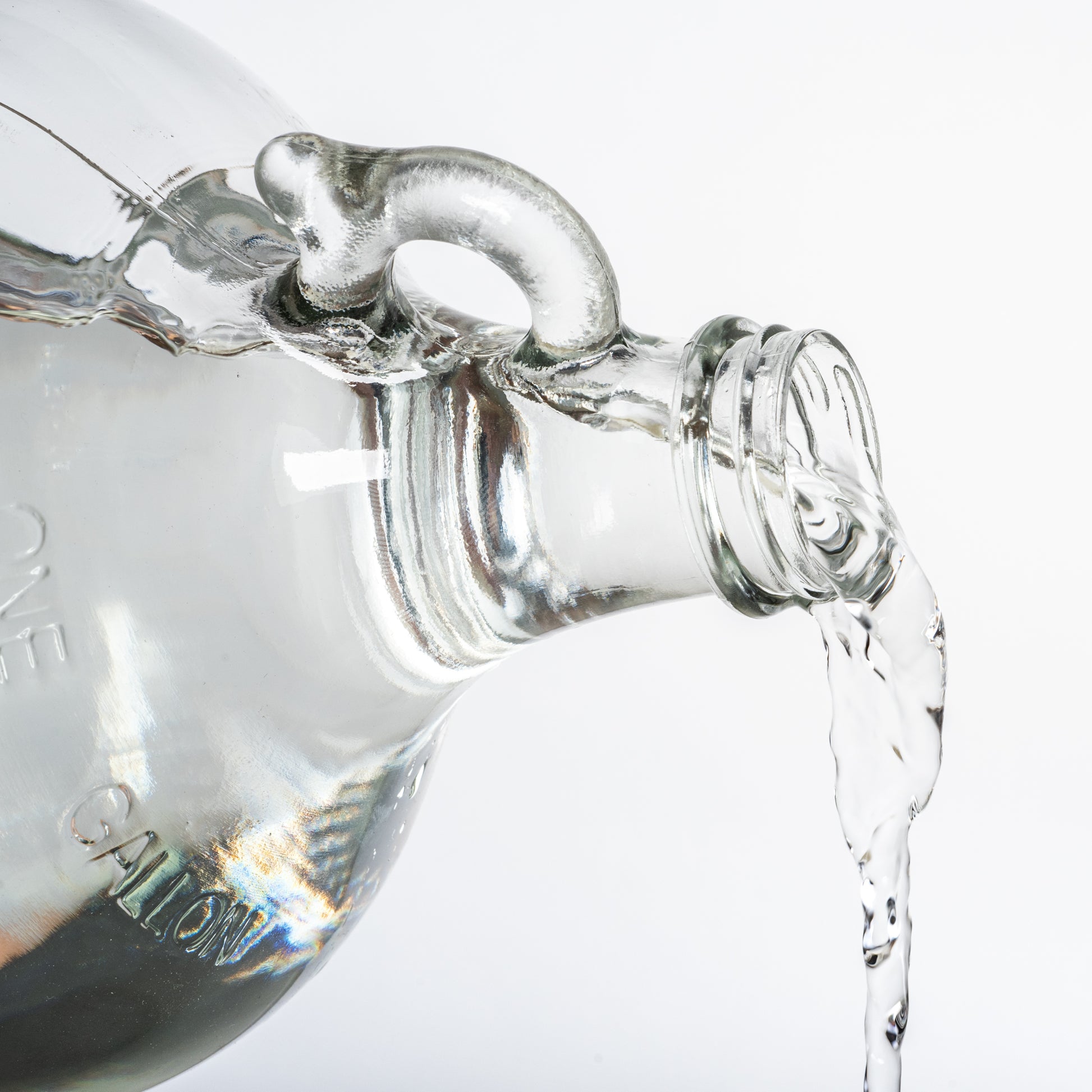 Clear glass container with a spout pouring liquid on a white background