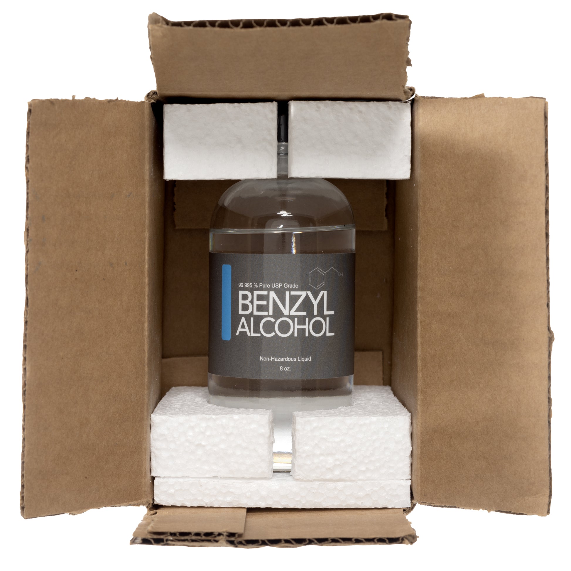 Clear glass bottle with a black plastic twist off cap. Label reads "Benzyl Alcohol non hazardous liquid" 8 oz. Product is shown inside of a brown cardboard box. There is Styrofoam on the top and the bottle of the glass bottle.  
