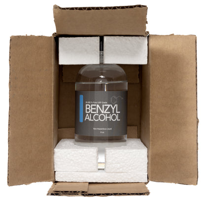 Clear glass bottle with a black plastic twist off cap. Label reads "Benzyl Alcohol non hazardous liquid" 8 oz. Product is shown inside of a brown cardboard box. There is Styrofoam on the top and the bottle of the glass bottle.  